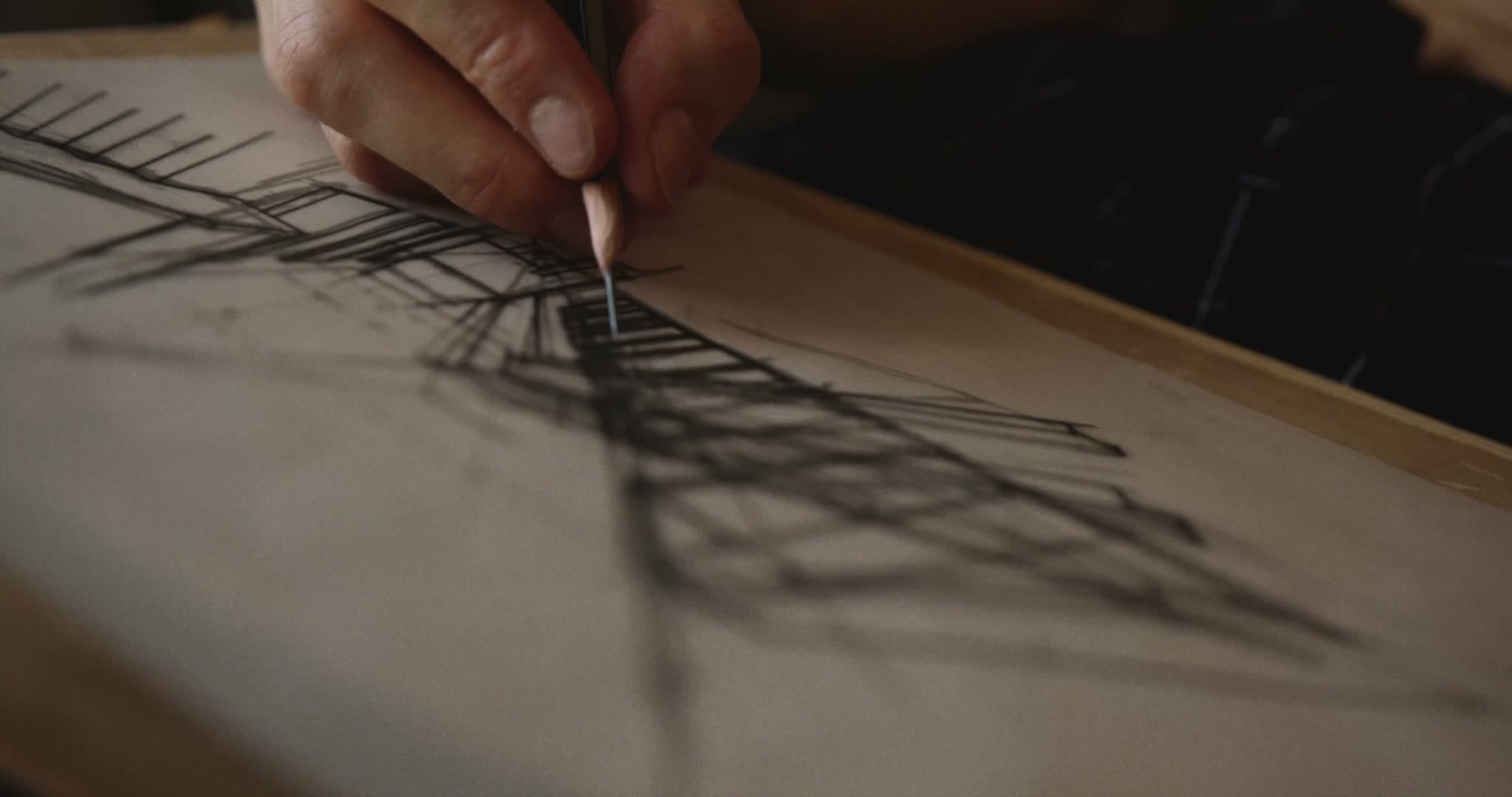 Close-up of a hand shading a graphite drawing on paper